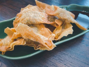 Derin kovulmuş Çin usulü wonton kıymalı ve yeşil seramik tabakta tatlı ve ekşi soslu.