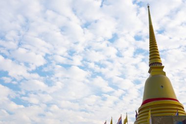 Mavi gökyüzü ve beyaz bulut arkaplanından görünen altın bir pagoda.