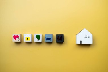 Ahşap bloklar aile simgeleri, yaşam, araba, sağlık, anahtar ve sarı arka planda ahşap ev. Sigorta konsepti