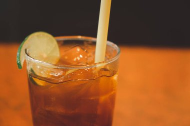 Limonlu buzlu çayı bir bardağın yanında limon dekoru ile kapat.