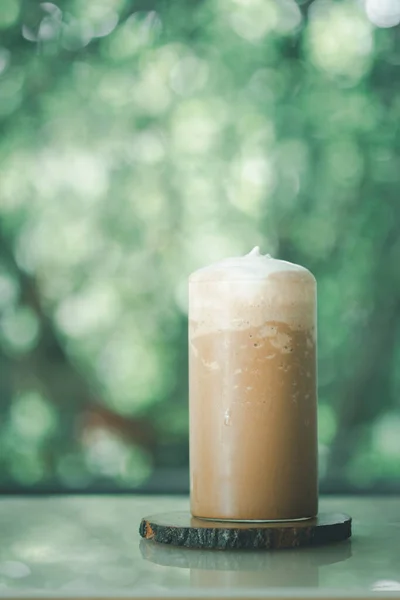 Iced coffee Mocha blended in tall glass placed on wood table against nature background. Relax time
