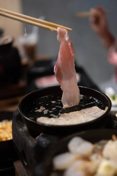 韓国のバーベキューで焼き豚の切り身を拾う箸 — ストック写真