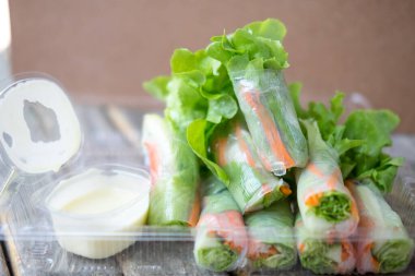 Maruldan, havuçtan, salatadan, salatalıktan ve erişteye sarılmış yeşil meşeden yapılmış salata ruloları. Salata sosuyla servis ediliyor.