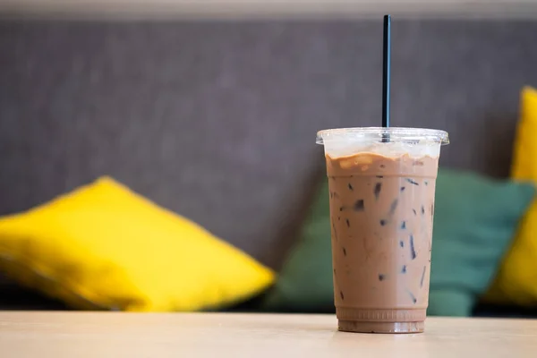 Iced mocha coffee in plastic cup showing the texture and refreshing look of the drink with sofa background