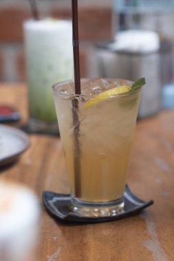 Buzlu limonata ve ahşap masada cam içinde limon.