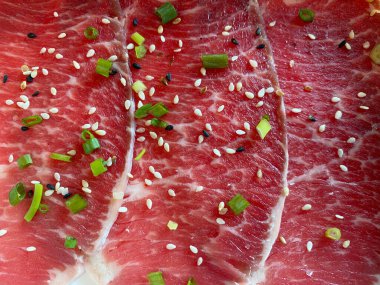 İnce dilimlenmiş çiğ et, siyah susam tohumları ve dilimlenmiş taze soğanla beyaz susam tohumları serpin.