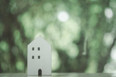 Mini ahşap ev modeli, doğadaki ahşap masa üzerinde. Mülk almayı ve en iyisini seçmeyi planlıyorlar..