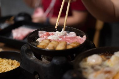 Eller ızgara domuz eti ızgarası için çubuk kullanıyor. Seçici odak