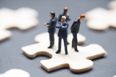 Group of miniature businessman standing on jigsaw puzzle piece finds a solution around. Joint path to problem-solving, find the way out exit of a difficult situation. Support, teamwork concept