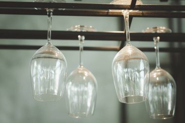Empty glass wine glasses on a rack above the counter bar. Selective focus.