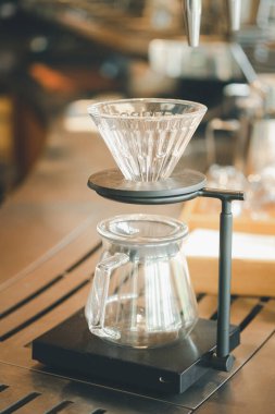Coffee dip tools with coffee dropping from dip cone into the glass jar in coffee shop