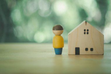 Wooden figures of people and a house on a nature background with copy space on the left. concept of affordable housing