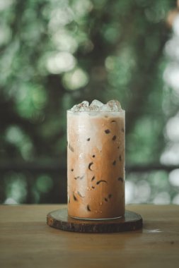 A glass of iced mocha coffee with milk against nature background.