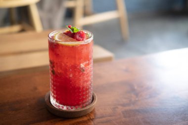 Raspberry ice cold refreshing cocktail with mint on wood table.