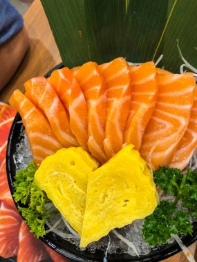 Japan raw salmon sashimi served with sweet egg on ice in Japanese food restaurant.