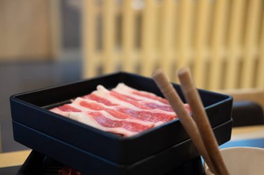 Shabu için taze çiğ et dilimi siyah tepside servis edilir.