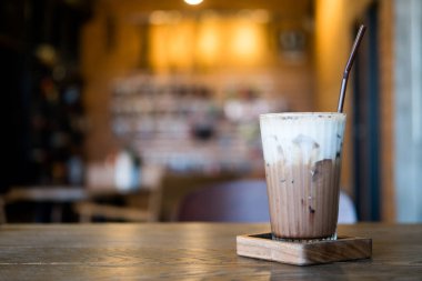 Süt köpüklü buzlu mocha ve bulanık ışıklı kafe.