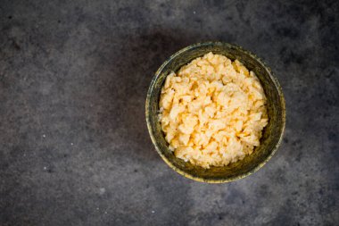 Sarı kasede çırpılmış yumurta. Arka planda taş var.