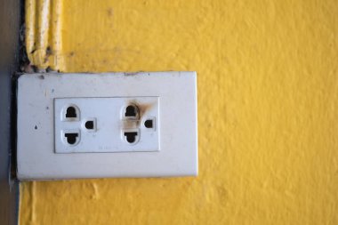 Eski elektrik prizleri sarı beton duvarda tehlikelidir..