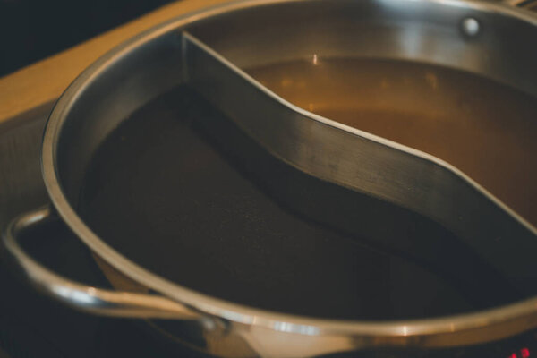 Specially made pot for soup base combo option to have two flavors of hot bouillon, close up