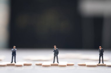 Yapboz üzerinde duran üç tane minyatür işadamı grubu. İş stratejilerinin kavramsal fotoğrafları