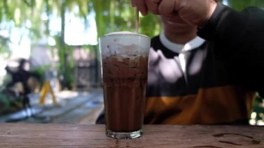 Kafede buzlu kahve içen bir adamın yavaş çekim sahnesi.