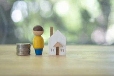 Para ve ahşap evlerin arasına yerleştirilmiş model ahşap insanlar. Konut ve konut için sermaye ve tasarruf, kredi ve ipotek, gayrimenkul konsepti için yatırım.