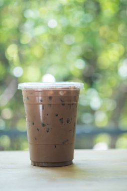 Plastik bahçedeki ahşap masada bir fincan buzlu kahve alır götürür.