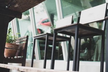 Restoranda ahşap bir masanın yanındaki tahta metal tabure..