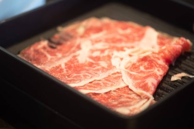 Japon Shabu restoranında dilimlenmiş çiğ wagyu bifteğini siyah tepside kapat.