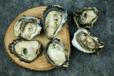 Taze çiğ istiridyeler, taştan siyah bir zeminde tepeden çekilmiş.