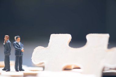 Tahta yapboz parçasının üzerinde duran minyatür işadamı. İş stratejisi kavramsal fotoğraf