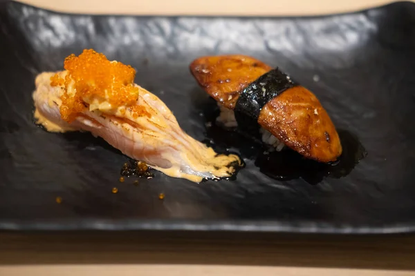 鲑鱼寿司和鹅肝寿司在一个黑色盘子里 靠近点 — 图库照片