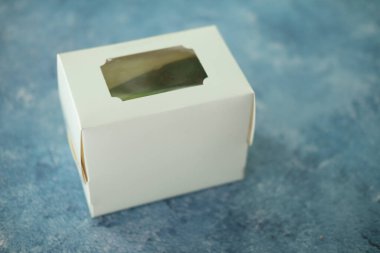 Mavi arka planda kapalı beyaz karton pasta kutusu