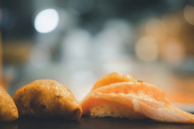 Siyah tabakta servis edilen soslu yanmış somon suşisi. Seçici odak