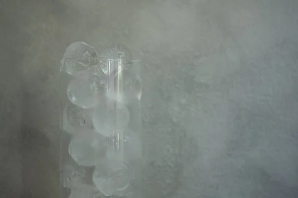 Close up of small ice ball in a tall glass against cement background