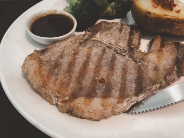 Izgara domuz pirzolası, beyaz tabağa yakın.