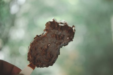 Elindeki çikolatalı dondurmayı ısır.