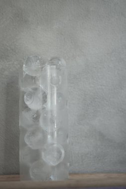 Büyük bardakta küçük bir buz topu çimento arka planda