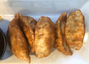 Kızarmış gyoza çıtır çıtır ve beyaz tabakta altın rengi. Üst görünüm