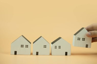 Mini ahşap ev modelini modelden seçen bir adam. Mülk almayı planlıyorlar. En iyisini seç konsepti