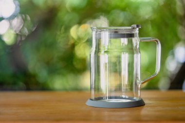 Şeffaf cam bardak doğaya karşı ahşap masaya yerleştirilmiş.