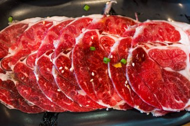 Shabu shabu hot pot ya da sukiyaki 'de pişirmek için özel taze et dilimlenmiş et yakın plan..