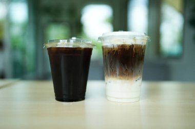 Kahve dükkanının ahşap masasında bir bardak buzlu kahve ve buzlu latte, menü fotoğrafçılığı..