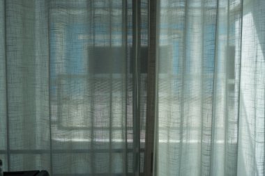 Oturma odası için katıksız beyaz perdeler, mahremiyeti korurken doğal ışık sağlıyor..