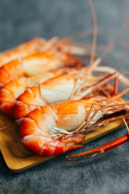 Ahşap tepside servis edilen haşlanmış dev nehir karidesleri. Kapat.