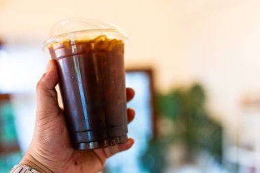 Elinde buzlu kahve ya da soğuk americano bardağı.