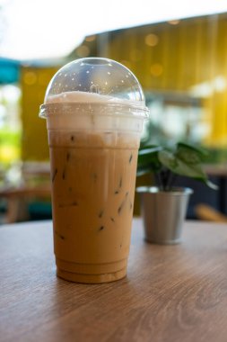 Iced latte coffee in plastic glass on wood table