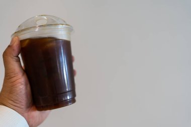 Buzlu sade kahve ya da bir adamın elindeki bardakta buzlu Americano kahvesi..