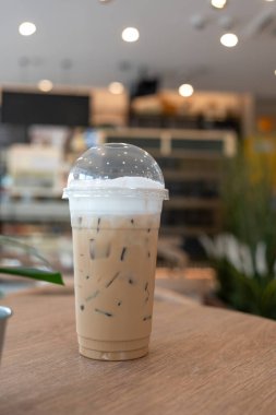 Tahta masadaki plastik bardakta buzlu kahve. Taze bir sabahta çalışmaya başla..